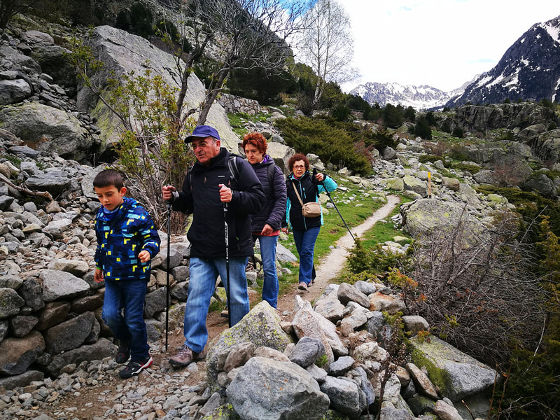 Família amb avis, mare i fill fent senderisme pels camins del Parc Nacional d'Aigüestortes.