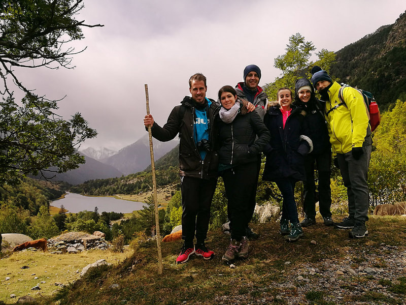 Grup d'amics amb l'Estany Llebreta al fons gaudint d'una excursió guiada al Parc Nacional d'Aigüestortes.