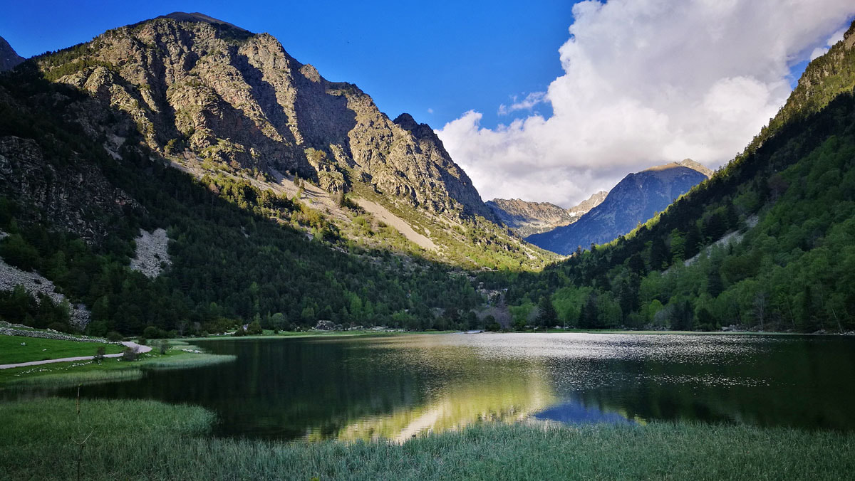 L'Estany Llebreta al capvespre envoltat de boscos mixtos on s'aprecien les valls d'origen galcial en forma de U dels Pirineus.